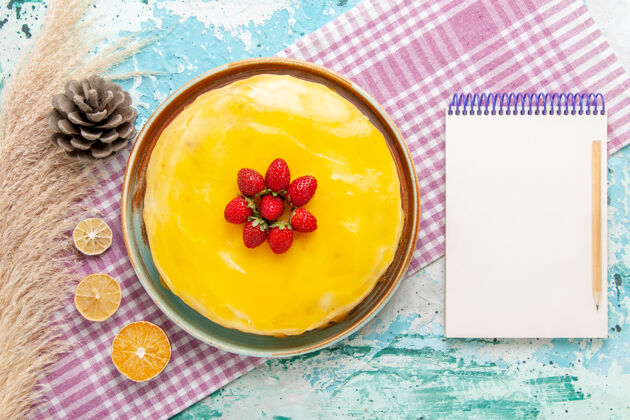 茶俯瞰美味的蛋糕 黄色糖浆和新鲜的红色草莓放在浅蓝色的饼干蛋糕上 烤甜甜的糖派茶蛋糕采购产品轻顶部
