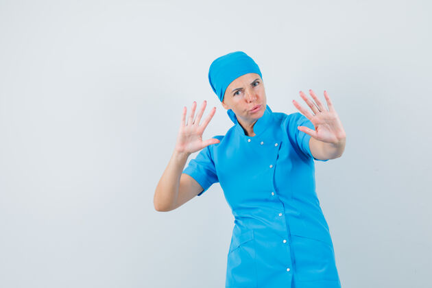 肖像女医生在蓝色制服前视图中显示停止手势以冷静下来诊断女士躺下