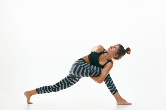 灵活运动型年轻女性 在白色工作室背景下做瑜伽练习适合灵活的女性模特练习健活方式的概念 身体和心理发展之间的自然平衡运动员课程教练