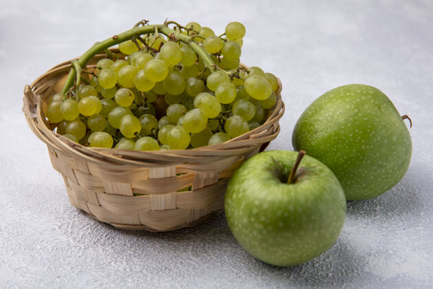 食物侧视图绿色的葡萄在一个篮子里 绿色的苹果在白色的背景上苹果藤蔓篮子