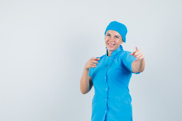 肖像女医生穿着蓝色制服指着摄像机 看上去很高兴前视图工作人员外科医生病人