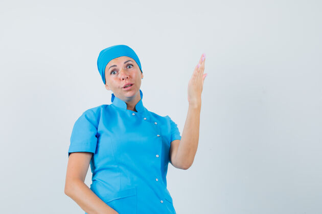 诊断女医生举起手臂和手掌 穿着蓝色制服 看上去很困惑前视图职员看台抚养