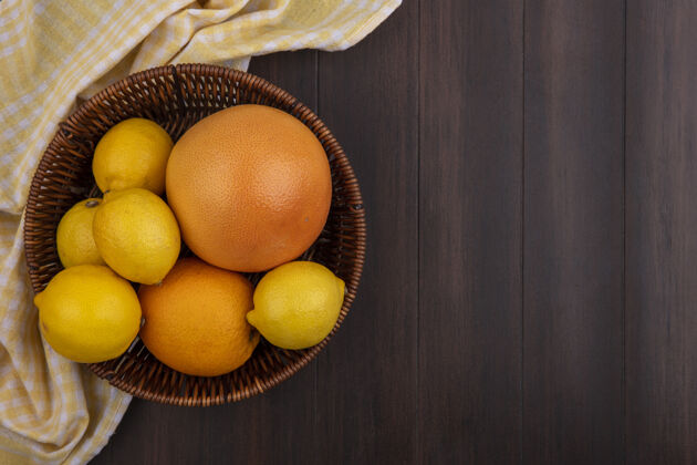 柠檬顶视图复制空间柠檬与橙色和葡萄柚在篮子与黄色格子毛巾木制背景空间木头风景