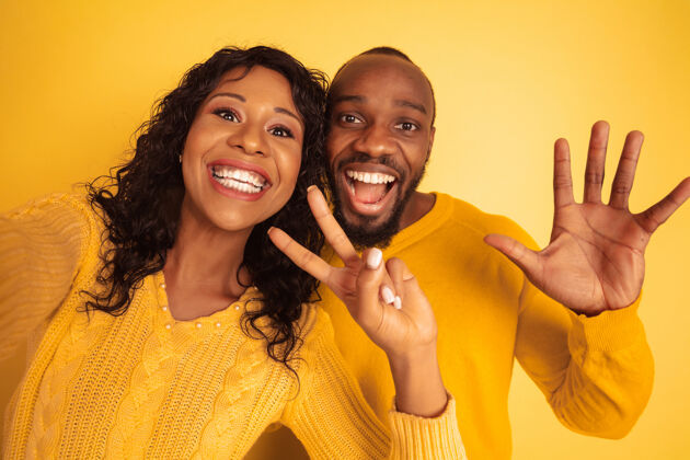 化妆品年轻感性的非裔美国人 穿着黄色背景的明亮休闲服美丽的情侣人类情感的概念 面部表情 关系 广告一起自拍人非洲表情