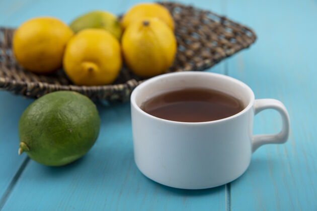 饮料蓝色木质背景上的一杯茶和一个桶上的新鲜柠檬的侧视图水桶壁板桌子