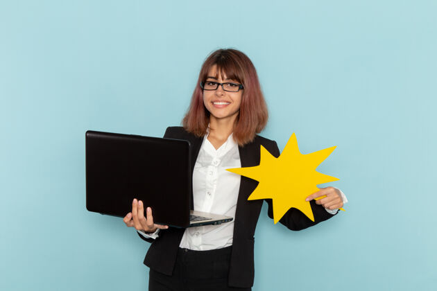 严格正面图：女上班族穿着西装 使用笔记本电脑 手持浅蓝色表面的黄色标志女商务人士工作工作