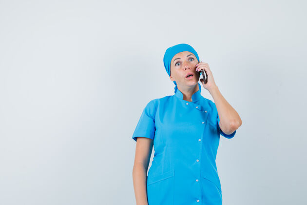 工作人员穿着蓝色制服的女医生正在讲手机 看上去很惊讶前视图临床护士女士