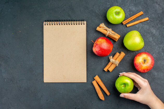 视图顶视图新鲜苹果肉桂棒笔记本苹果在女性手中黑暗的表面学习黑板学校