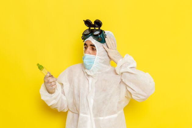 工人正面图身着特殊防护服的男科学工作者手持喷雾瓶在浅黄色表面套装喷雾服装