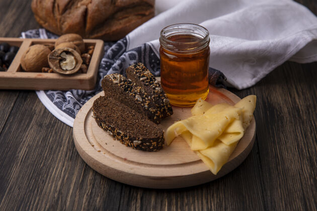 黑色正面图蜂蜜在一个罐子里 黑面包和奶酪放在一个架子上 胡桃木背景架子食物奶酪