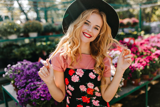 肖像快乐的女人卷发摆在橘子园壮观的欧洲模特站在鲜花旁边花花店笑