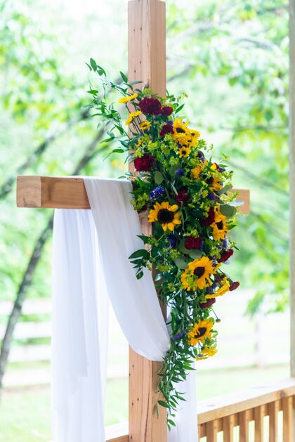 花瓣垂直特写镜头上的一个白色织物覆盖的木制十字架花束浪漫花叶
