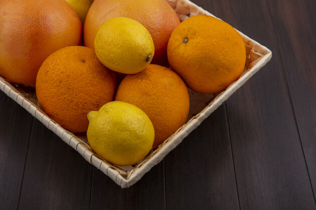 橘子正面图木制背景上放着柠檬和葡萄柚的篮子里的橙子五颜六色葡萄柚篮子