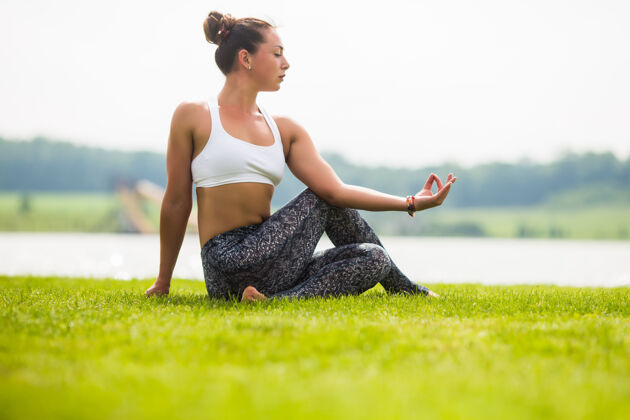 阳光美丽的女人在绿色公园做瑜伽练习放松快乐健康