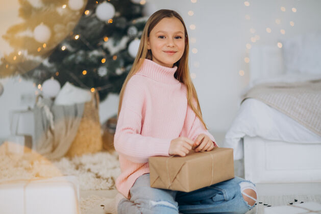 年轻可爱的女孩拿着圣诞礼物在圣诞树旁圣诞树青少年人