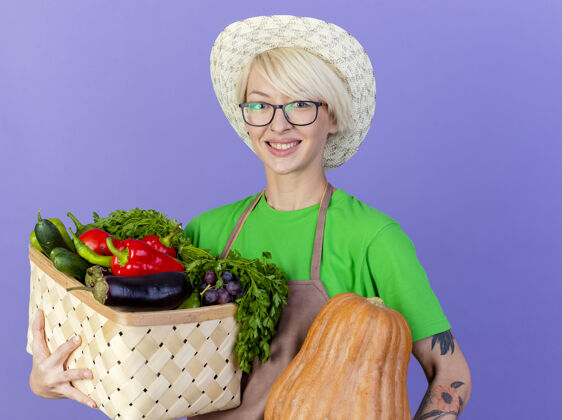 蔬菜一位年轻的园丁 围着围裙 戴着帽子 手里拿着装满蔬菜的箱子年轻板条箱头发