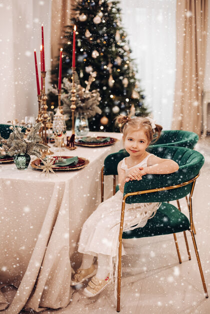 圣诞节穿着裙子的孩子在餐桌前的绿色椅子上舒服地坐着装饰圣诞快乐柔软