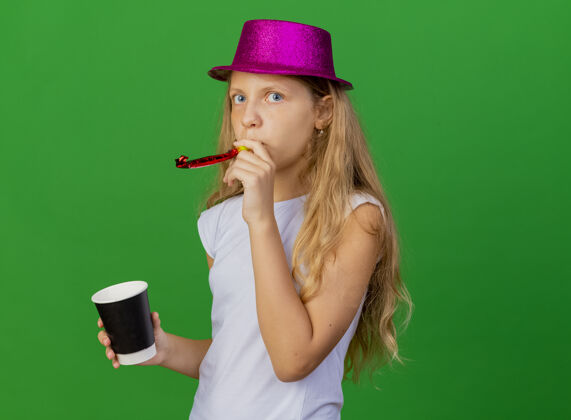 帽子戴着节日帽子的漂亮小女孩拿着智能手机吹口哨女孩派对生日