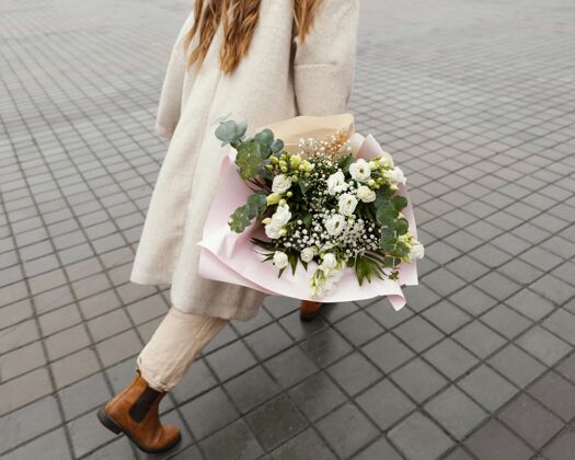 春天优雅的女子手持花束漫步在城市户外春天女人