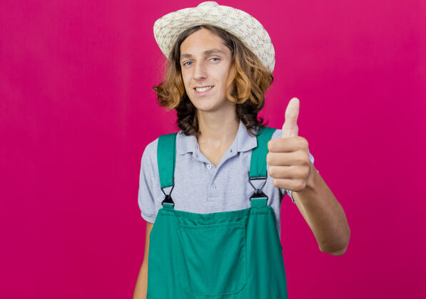 表演年轻的园丁穿着连体衣戴着帽子微笑着竖起大拇指微笑花园连身衣