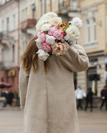 春天在春天 一位优雅的女士手持一束鲜花站在户外花女人户外