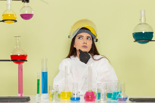 正面前视图穿着特殊防护服的女化学家在浅绿色表面思考医学女专业
