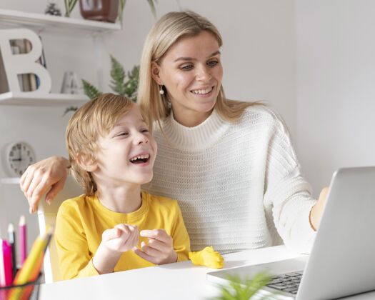 娱乐笑脸男孩和妈妈在家里用笔记本电脑设备年轻人电子