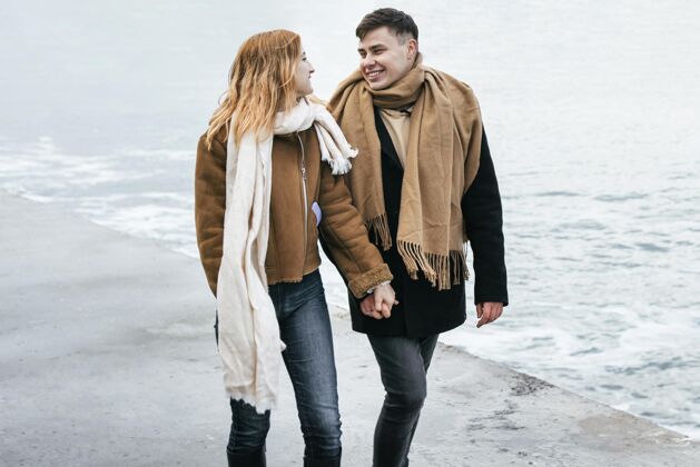 水平冬天 一对情侣手牵着手在海滩边散步女人业余爱好冬天