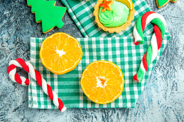 毛巾俯视图切橘子圣诞树糖果绿色白色方格厨房毛巾在灰色的桌子上视图帽子新鲜