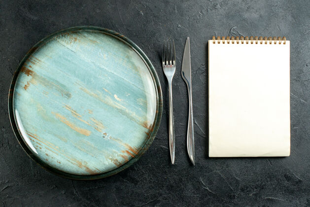 刀顶视图圆碟钢叉和餐刀笔记本上的黑表粉末空白古董