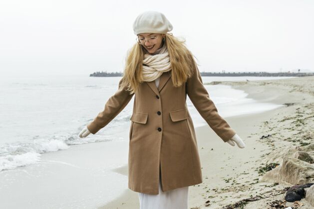 业余爱好冬季海滩上戴手套的女人的正面图旅行冒险探索
