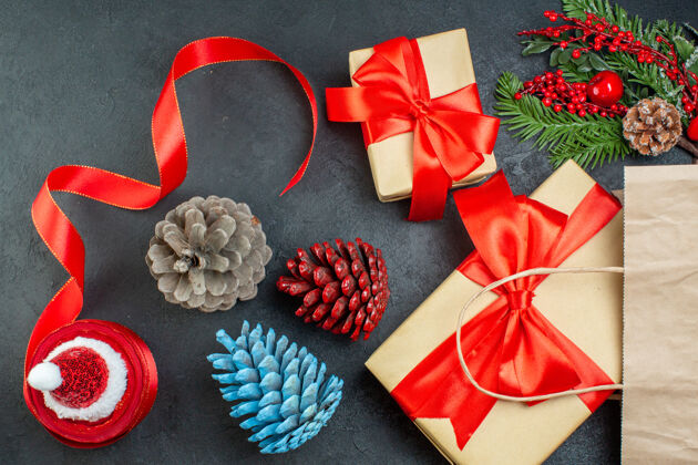 圣诞节一卷红丝带针叶树球果和礼物冷杉树枝在黑暗背景的水平视图圆锥体视图树枝