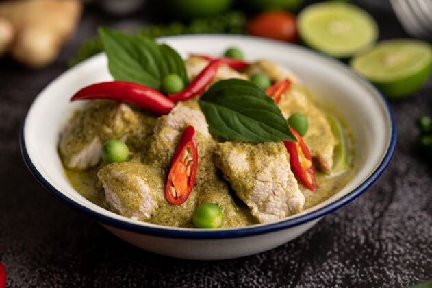 餐饮猪肉绿色咖喱在一个白色的碗与香料在一个黑色的水泥背景餐传统泰国食物