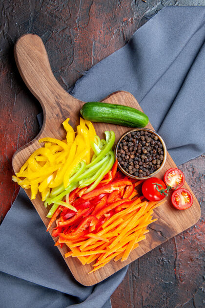 胡椒顶视图五颜六色的切辣椒黑胡椒西红柿黄瓜在砧板上在深红色的桌子上蓝色披肩辣椒观点沙拉