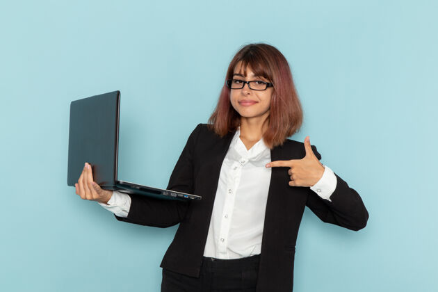 秘书正面图：女上班族拿着她的笔记本电脑在蓝色的表面上忙前面电脑