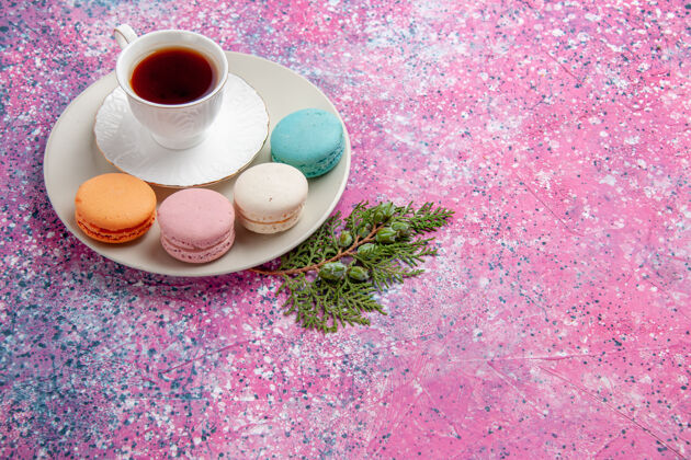 茶碟正面是一杯茶 粉色表面有五颜六色的法国马卡龙饼干甜食生的