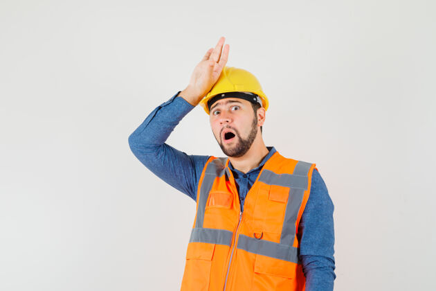职业年轻的建筑工人手挽着手 头上穿着衬衫 背心 戴着头盔 面带渴望 俯瞰前方建筑工人工业人