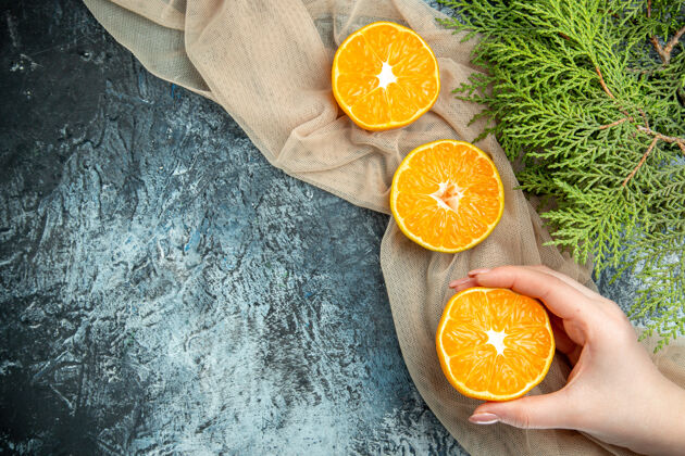 景观俯视图切割橙色在女性手松果在米色披肩在黑暗的表面自由空间维生素果汁甜橙