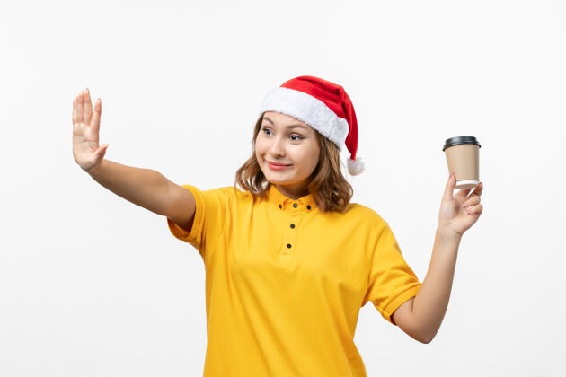 送货正面图年轻女快递员用咖啡在白墙上统一服务送货服务年轻的女信使圣诞节
