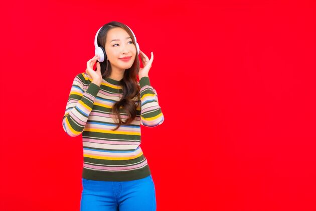 应用程序肖像美丽的亚洲年轻女子使用智能手机和耳机听音乐享受手机智能