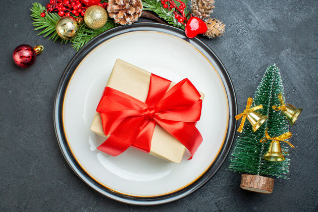 礼品盒上图是餐盘上的礼品盒圣诞树冷杉枝针叶树锥黑色背景晚餐圆锥体盘子