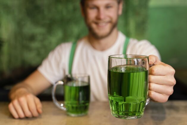 三叶草英俊的笑脸男人用饮料庆祝圣帕特里克节饮料爱尔兰幸运