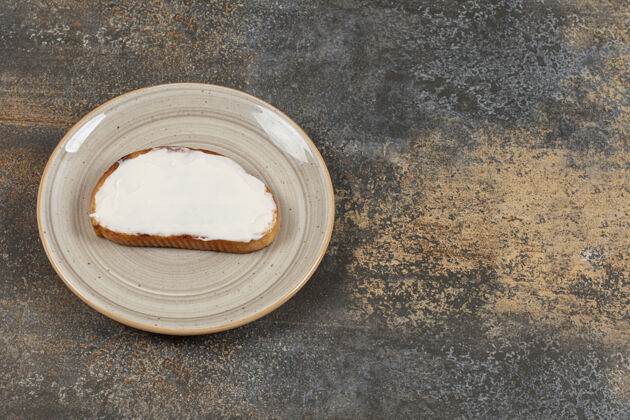 酸的在陶瓷盘子上放一片烤面包和酸奶油酸奶油抹酱正餐