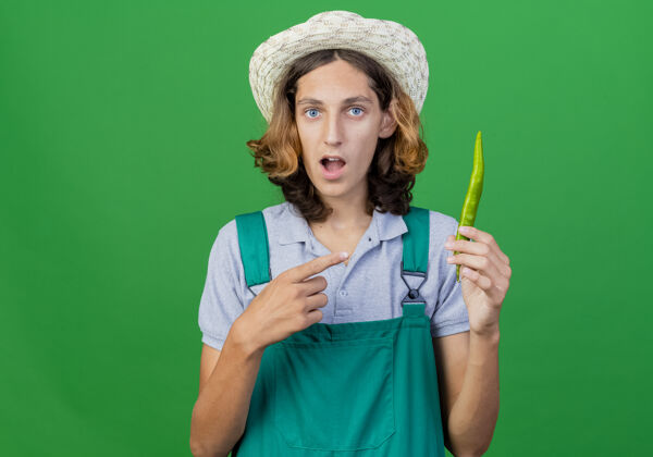 指向年轻的园丁穿着连体衣戴着帽子拿着青椒指着男人辣椒绿色