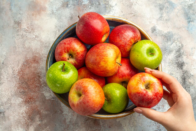维生素顶视图红色和绿色苹果在碗苹果在女性手裸体表面苹果梨视图