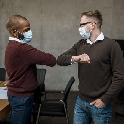 问候侧视图中的男子肘部相互敬礼在会议期间 并戴着医用口罩集会公司工作