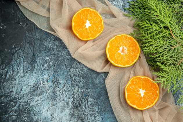 切片俯瞰剪橘子上米色披肩松枝上深色表面的自由空间切橘子顶部维生素