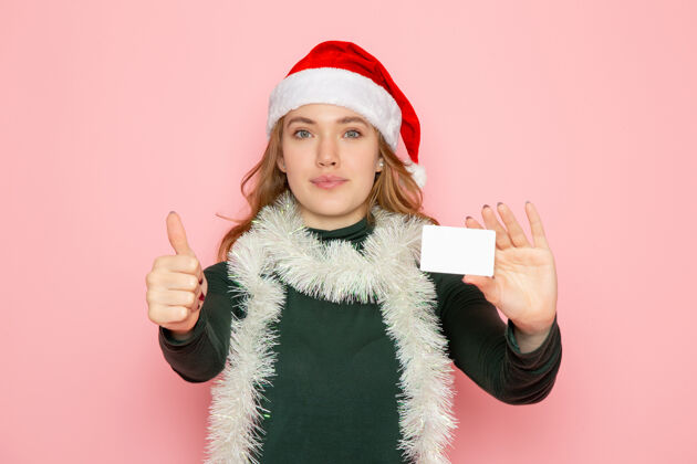 围巾正面图年轻女性手持银行卡在粉色墙面上的彩色模特节日圣诞新年感慨帽子看法银行