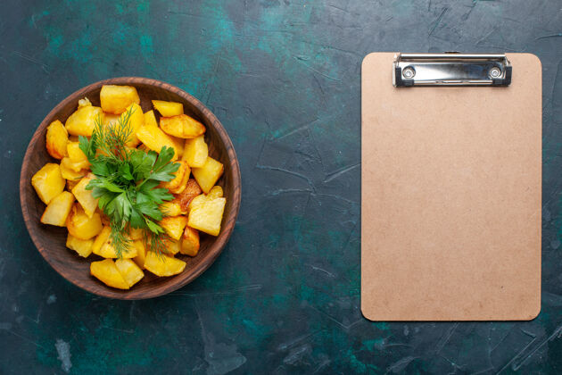 烹饪俯视图烹饪土豆片美味的一餐 在深蓝色桌子上的棕色盘子里放着绿色的记事本托盘里面绿色
