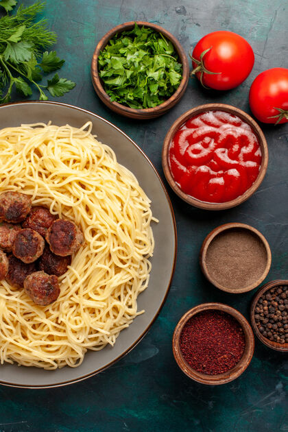 餐在深蓝色的桌子上俯瞰不同调味料的意大利熟面食面团调味品肉